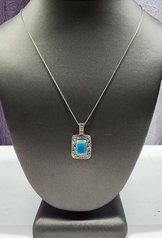 Own a piece of vintage beauty with this stunning pendant necklace. Crafted from 925 sterling silver, it features a rectangular cabochon-cut turquoise stone surrounded by marcasite accents in a bezel setting. Its 18-inch box chain with spring ring closure makes it the perfect accessory for any occasion, whether it be Mother's Day, Christmas, or just a day at the beach. The pendant has a timeless style and is signed by MO, making it an original piece from Thailand. This necklace is a must-have for any jewelry collection. Please review the pictures. They are a part of the description and ask any questions before purchase. Thank you! Elegant Turquoise Jewelry With Rectangular Stone, Elegant Turquoise Necklace With Rectangular Pendant, Elegant Turquoise Necklace With Square Pendant, Elegant Turquoise Square Pendant Necklaces, Elegant Turquoise Square Pendant Necklace, Elegant Turquoise Rectangular Stone Jewelry, Elegant Nickel-free Turquoise Necklace, Vintage Beauty, Box Chain