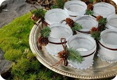 small glass jars with pine cones and twine tied around them on a silver platter