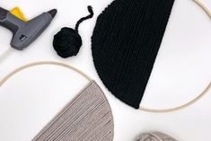 yarn, scissors and thread laid out on a white surface with some knitting supplies nearby