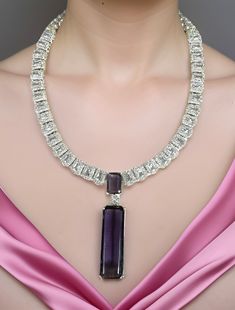 Lustrous Pink CZ stone with crystal-work combines with a delicate White gold frame to immediately effuse any ensemble with a dramatic dose of evening elegance! The set includes a pair of matching dangle earrings. Available in Pink and Amethyst Purple Dimension: 7" long, 2.25" pendant, 2.25" earrings Weight: 2.8 oz, w/ packaging 3.5 oz Luxury Purple Diamond Necklace, Purple Diamond Necklaces For Wedding, Purple Diamond Necklace For Wedding, Luxury Purple Jewelry With Stones, Elegant Purple Diamond Necklace, Purple Diamond Wedding Necklace, Luxury Purple Stone Jewelry, Luxury Amethyst Necklace With Diamond Accents, Luxury Purple Jeweled Jewelry