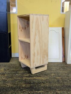 a wooden cabinet sitting on top of a carpeted floor next to a wall with yellow walls