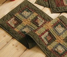 three placemats on a wooden table with an apple in the foreground and another piece of quilted material to the side