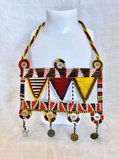 Please Read Full Description This vintage beaded Maasai necklace is a vibrant and authentic piece of hand crafted art from East Africa.  The Maasai artisans use a traditional technique with colorful glass beads intricately woven into beautiful patterns that reflect the rich cultural heritage of the Maasai people.  The necklace features eye-catching yellow, black, red and white beads sewn on a sturdy rigid base to keep the beads in place.  It is an elegant, statement-making piece of art.  To wear, the necklace slips over the head and hangs beautifully across the chest.  This necklace is in excellent condition.  All of the beads are intact. Measurements: Body of the necklace is 5 1/2" x 5 1/2".  The beaded string that slips around the neck is 21". FREE DOMESTIC SHIPPING   My vintage finds ar Maasai People, Bead Sewing, Maasai, Art To Wear, East Africa, Beaded Necklaces, Cultural Heritage, White Beads, Traditional Techniques