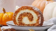 a cinnamon roll sitting on top of a white plate next to pumpkins and gourds