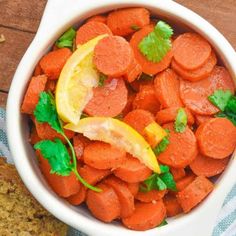 a bowl filled with carrots, lemon and cilantro on top of a table