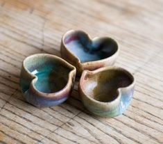 three heart shaped bowls sitting on top of a wooden table