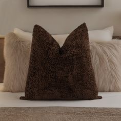 a brown pillow sitting on top of a bed next to a framed picture above it