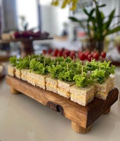 a wooden tray filled with lettuce on top of a white table next to other food