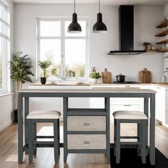 a kitchen with two stools and an island in front of the window, next to a potted plant