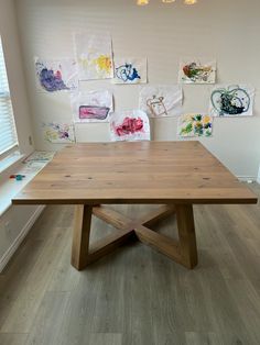 a wooden table sitting on top of a hard wood floor next to a white wall