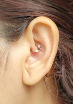 a woman's ear is shown with a tiny nose ring