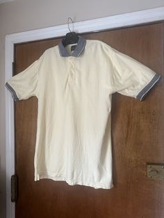 a white shirt hanging on a door with a blue collared neckline and two gray trims