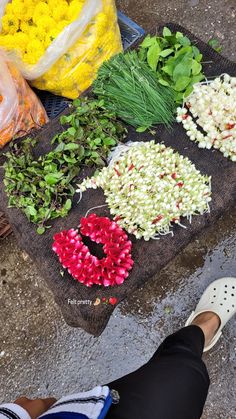 there are many different types of flowers on the ground and one person is standing next to it