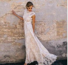 a woman in a white dress leaning against a wall