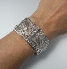 Here is an exceptional Art Nouveau completely handmade silver filigree bracelet circa 1890. The workmanship here is reminiscent of 18th century filigree in the quality and intricacy of this amazing piece. Each panel is entirely made by hand with silver wire twisted and wound into a fern and frond design each bouquet tied with a feminine bow. Amazingly each panel is not flat but the silver lace design is raised in relief with the central fern frond sitting higher to the rest of the panel. When th Victorian Style White Gold Bracelets For Formal Occasions, Victorian White Gold Bracelets For Formal Occasions, Elegant Cuff Bracelet With Intricate Design For Formal Events, Elegant Cuff Bracelet With Intricate Design For Formal Occasions, Victorian Bangle With Intricate Design For Formal Occasions, Elegant Hallmarked Sterling Silver Bracelet For Ceremonial Use, Elegant Hallmarked Sterling Silver Bracelet For Ceremonial Occasions, Formal Victorian Bangle With Intricate Design, Elegant Etched Bangle For Formal Occasions