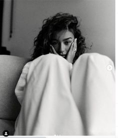 a black and white photo of a woman laying in bed with her hands on her face