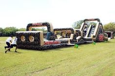 an inflatable obstacle is set up on the grass with two men running towards it