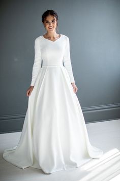 a woman in a white wedding dress posing for the camera with her hands on her hips