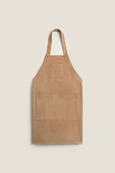 a brown apron hanging on the wall with an empty pocket in front of it and a white background