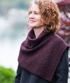 a woman with curly red hair wearing a knitted shawl and looking off into the distance