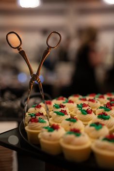 a pair of scissors cutting through cupcakes on a tray