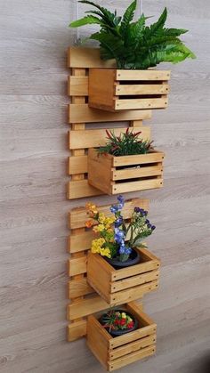 three wooden planters with plants in them hanging on the wall next to a potted plant