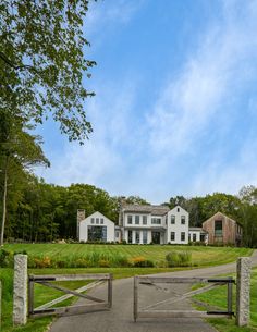 a large white house sitting on the side of a lush green field next to a road