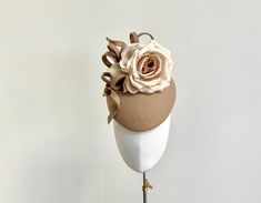 A beautiful statement fascinator in a soft shade of camel. Made in luxurious felt, this elegant headpiece features a stunning handmade silk dupion rose in deep cream that sits to one side and is entwined with twists of felt in the same beautiful shade of caramel.  An extremely flattering shape to wear, this pillbox measures 20cm front to back and 17cm side to side. It is fitted with a fine elastic in a shape to blend in with your own hair, which sits to the back of the head and underneath the ha Elegant Brown Mini Hat With Curved Brim, Elegant Brown Felt Hat, Elegant Beige Felt Hat With Curved Brim, Elegant Brown Hat For Royal Ascot, Brown Hats For Kentucky Derby Wedding, Brown Wedding Hats For Kentucky Derby, Elegant Brown Adjustable Headpiece, Brown Kentucky Derby Wedding Hat, Elegant Adjustable Brown Headpiece