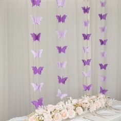 the table is set up for a party with purple and white butterflies hanging from the ceiling