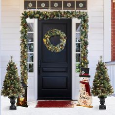 a black front door decorated with christmas wreaths and lights