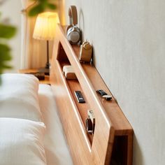 a wooden shelf with cell phones on it next to a white bed in a bedroom