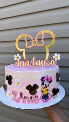 a pink and yellow cake with minnie mouse topper