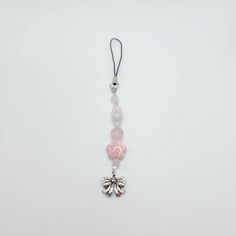 a pink and white beaded necklace hanging from a cord on a white surface with a black string