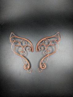 two metal wings on a black surface with one in the shape of an animal's tail