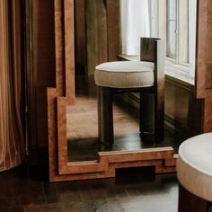 a mirror sitting on top of a wooden floor next to a table with a stool