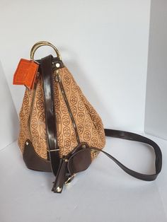 This beautiful backpack sling bag from Marino Orlandi is a perfect blend of elegance and functionality. With a brown leather exterior, printed croc embossing, and gold-plated hardware, this bag is sure to turn heads. The cylinder shape and adjustable strap make it suitable for a variety of occasions, from travel to formal events. The bag features multiple inner and outer pockets, bottom studs for stability, and a lined interior. The logo embossed pattern and theme options, like motorcycle and bohemian, make it a statement piece. Made in Italy with high-quality leather, this bag is a must-have for any fashion-forward individual. Beautiful Backpacks, Embossed Pattern, Cylinder Shape, High Quality Leather, Sling Bag, Tan Brown, Formal Event, Leather Backpack, Bag Making