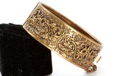 "DESCRIPTION: This antique bangle bracelet is designed to create this Victorian Revival piece, featuring a brass-tone finish with intricate details that are reminiscent of the Victorian era. The ornate design is a perfect accessory for those who appreciate vintage and antique jewelry. The bangle is sturdy and durable, making it perfect for everyday wear. This piece has some wear on the brass tone and is being secured by a push pull clasp. This measures 2 1/2\" diameter by 1 1/2\" wide. SHIPPING: Luxury Victorian Gold Bracelet For Anniversary, Victorian Gold Bangle Bracelet With Intricate Design, Victorian Bangle With Intricate Design For Formal Occasions, Ornate Engraved Gold Bangle Bracelet, Formal Victorian Bangle With Intricate Design, Victorian Filigree Bangle, Gold Victorian Cuff Bracelet With Intricate Design, Antique Bangle With Intricate Design For Formal Occasions, Elegant Antique Gold Brass Cuff Bracelet