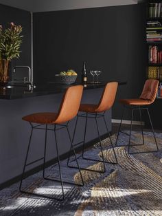 three orange chairs sitting in front of a bar