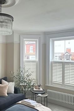 a living room filled with furniture and two windows covered in shades of white shutters