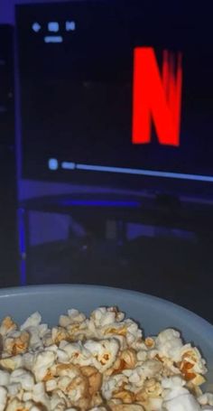 a bowl filled with popcorn sitting on top of a table next to a tv screen