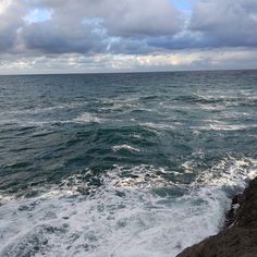 the ocean is very choppy and blue with white clouds in the sky above it