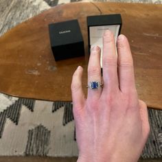 a person's hand with a ring on it and a box in the background