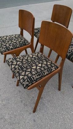 four wooden chairs with patterned upholstered seats sit on the sidewalk next to each other