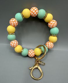 an orange, yellow and green beaded bracelet with a pair of gold pliers