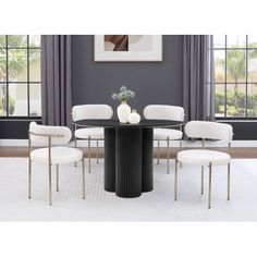 a dining room table with four chairs around it and a vase on the table top