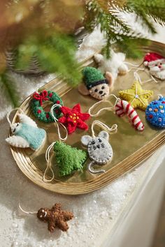 christmas ornaments are sitting on a tray next to a pine tree and some other decorations