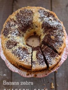 a bundt cake with powdered sugar on top sitting on a pink paper plate