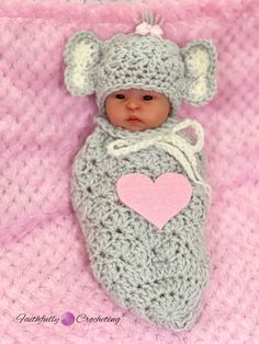 a baby wearing a crochet hat and blanket with a heart in the middle