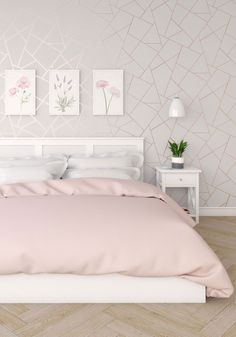 a bed with pink sheets and pillows in a bedroom next to a white nightstand table