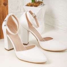 a pair of white high heeled shoes sitting on top of a table next to a potted plant